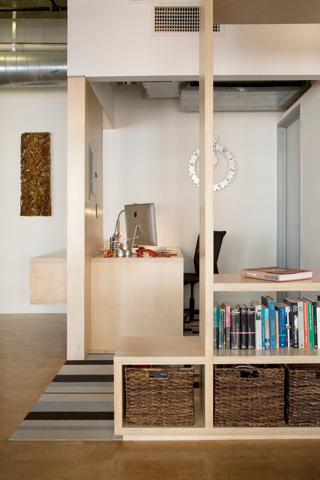 Diseño de despacho pequeño sin chimenea con paredes blancas, suelo de corcho y escritorio empotrado