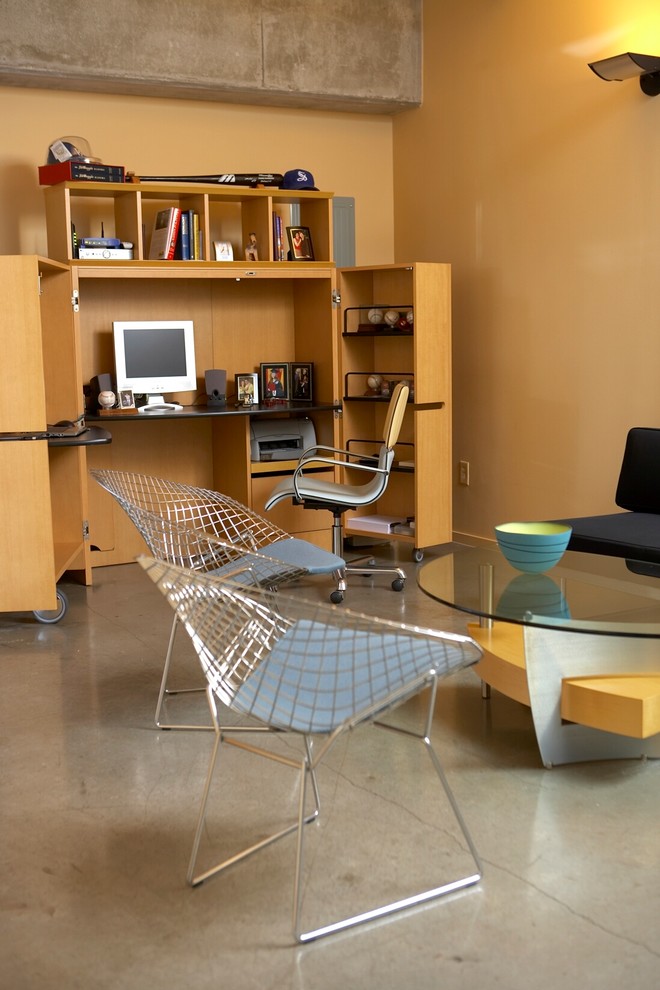 Immagine di un grande ufficio minimal con pareti gialle, pavimento in cemento, nessun camino e scrivania autoportante