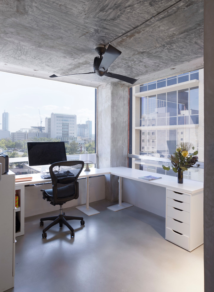 Diseño de despacho urbano de tamaño medio con paredes grises, suelo de cemento y escritorio independiente