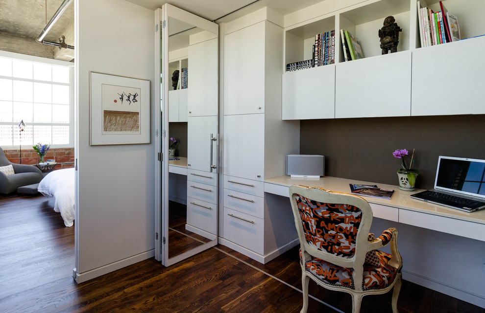 Home office - industrial built-in desk dark wood floor home office idea in Houston with white walls