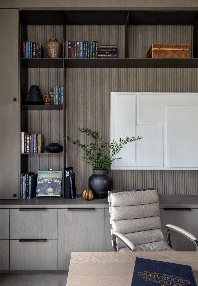 Geräumiges Klassisches Arbeitszimmer mit Arbeitsplatz, brauner Wandfarbe, braunem Holzboden, freistehendem Schreibtisch, braunem Boden und Wandpaneelen in Houston
