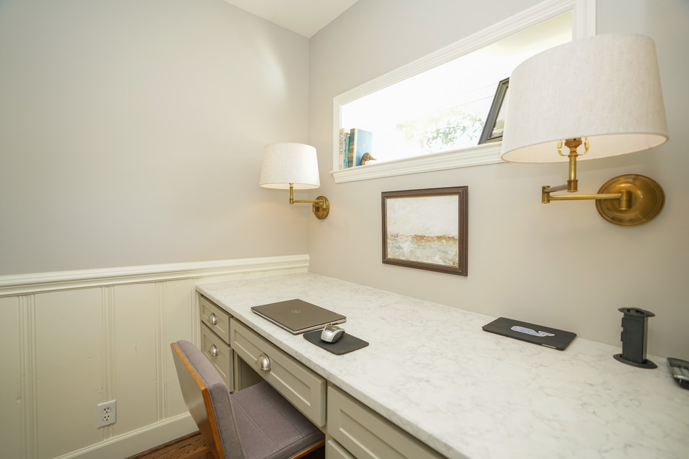 Imagen de despacho de estilo americano pequeño con paredes blancas, suelo de madera en tonos medios, escritorio empotrado y suelo marrón