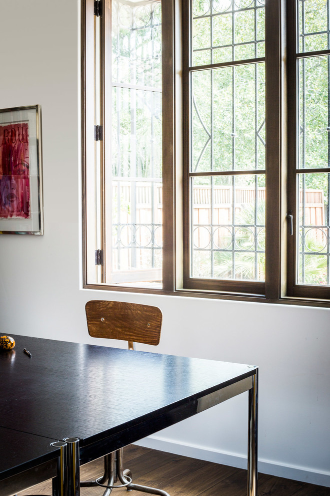 Foto de despacho mediterráneo de tamaño medio con paredes blancas, suelo de madera oscura, escritorio independiente y suelo marrón