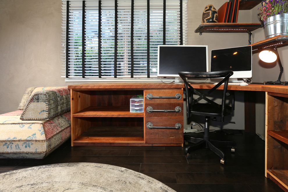 Großes Industrial Arbeitszimmer mit Arbeitsplatz, beiger Wandfarbe, dunklem Holzboden und Einbau-Schreibtisch in Los Angeles