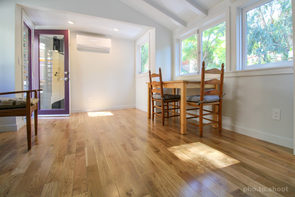 Idee per una stanza da lavoro classica di medie dimensioni con pareti bianche, pavimento in legno massello medio, scrivania autoportante, pavimento marrone e travi a vista