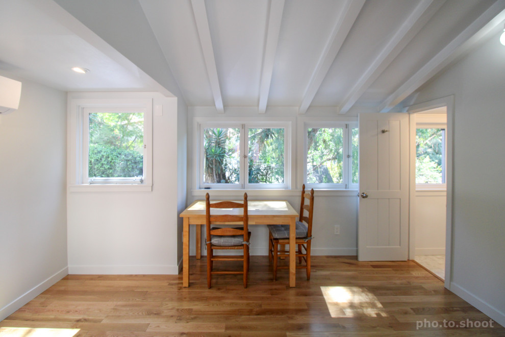 Cette image montre une salle à manger traditionnelle de taille moyenne avec un mur blanc, un sol en bois brun, un sol marron et poutres apparentes.