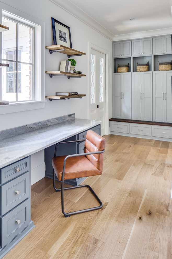Foto de despacho clásico con paredes blancas, suelo de madera clara, escritorio empotrado y suelo beige