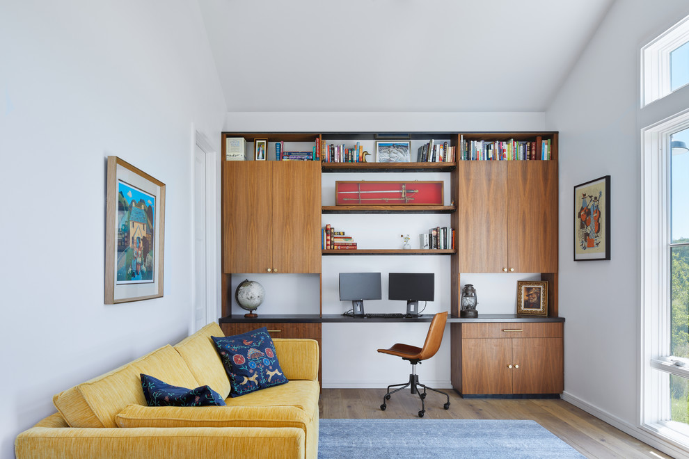 Cette photo montre un bureau scandinave avec un mur blanc, un sol en bois brun, un bureau intégré et un sol marron.