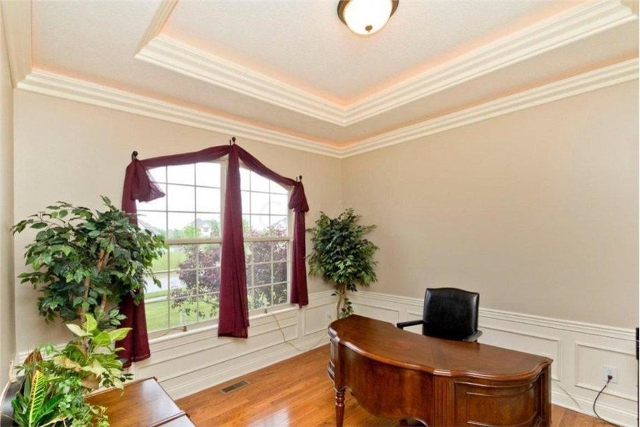 Ejemplo de despacho clásico grande sin chimenea con paredes beige, suelo de madera clara y escritorio independiente