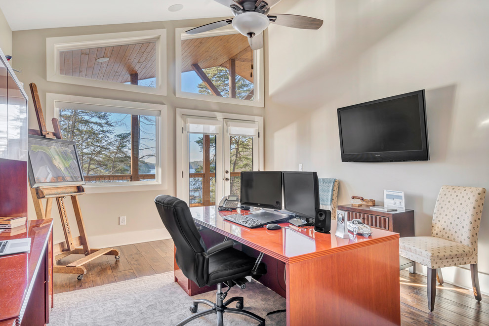 Ejemplo de despacho de estilo americano de tamaño medio sin chimenea con suelo de madera oscura, escritorio independiente y suelo marrón
