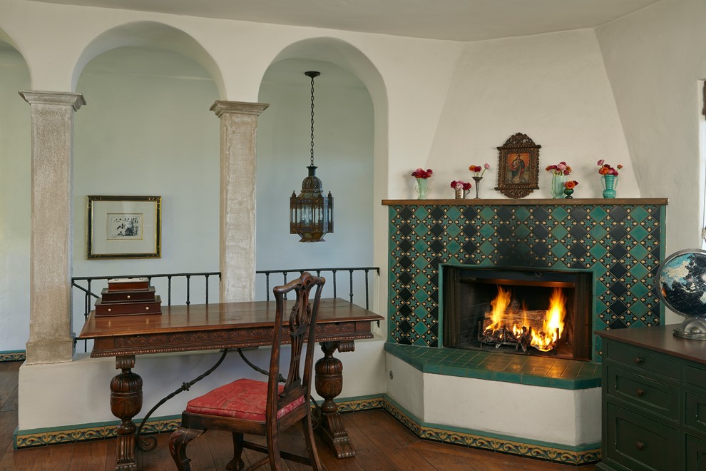 ロサンゼルスにあるサンタフェスタイルのおしゃれなホームオフィス・書斎 (ベージュの壁、濃色無垢フローリング、コーナー設置型暖炉、タイルの暖炉まわり、自立型机) の写真