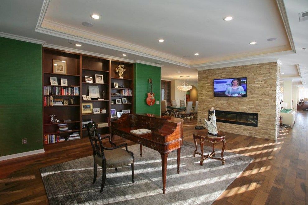 Photo of an eclectic study in Nashville with green walls, medium hardwood flooring, a standard fireplace, a stone fireplace surround and a freestanding desk.