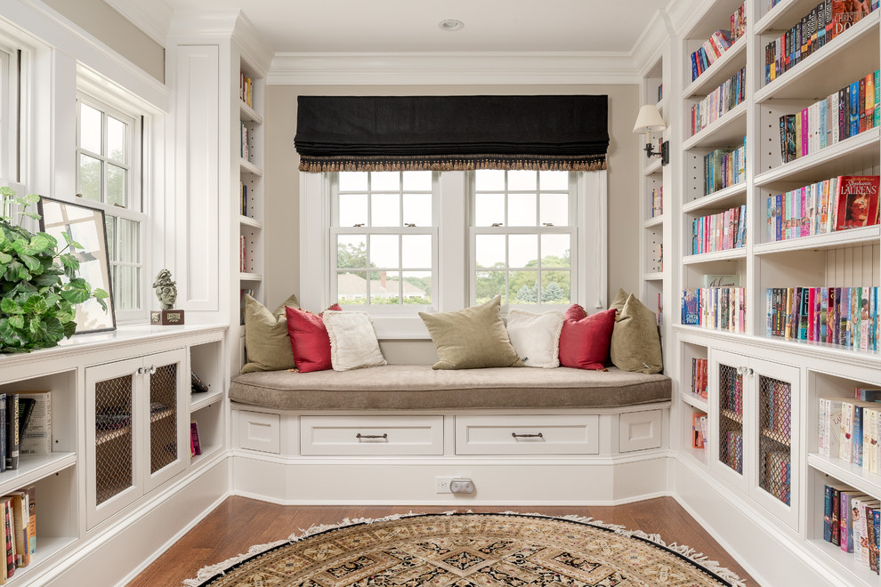 Esempio di un ampio studio stile marino con libreria, pavimento in legno massello medio, scrivania incassata e pareti beige