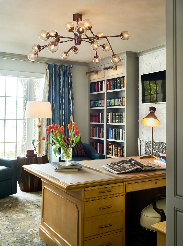 Inspiration för stora klassiska hemmabibliotek, med grå väggar, mellanmörkt trägolv, en standard öppen spis, en spiselkrans i sten, ett fristående skrivbord och brunt golv