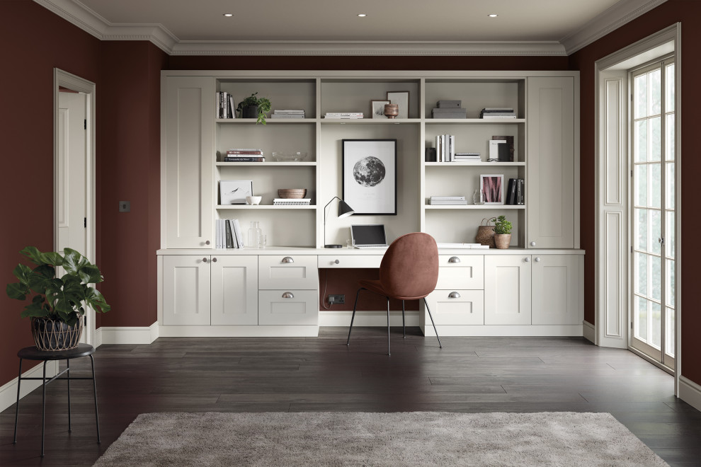 Modelo de despacho tradicional de tamaño medio con paredes rojas, suelo de madera en tonos medios, escritorio empotrado y suelo marrón
