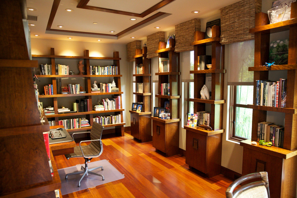 Exotisk inredning av ett mellanstort arbetsrum, med ett bibliotek, beige väggar, mellanmörkt trägolv och ett inbyggt skrivbord