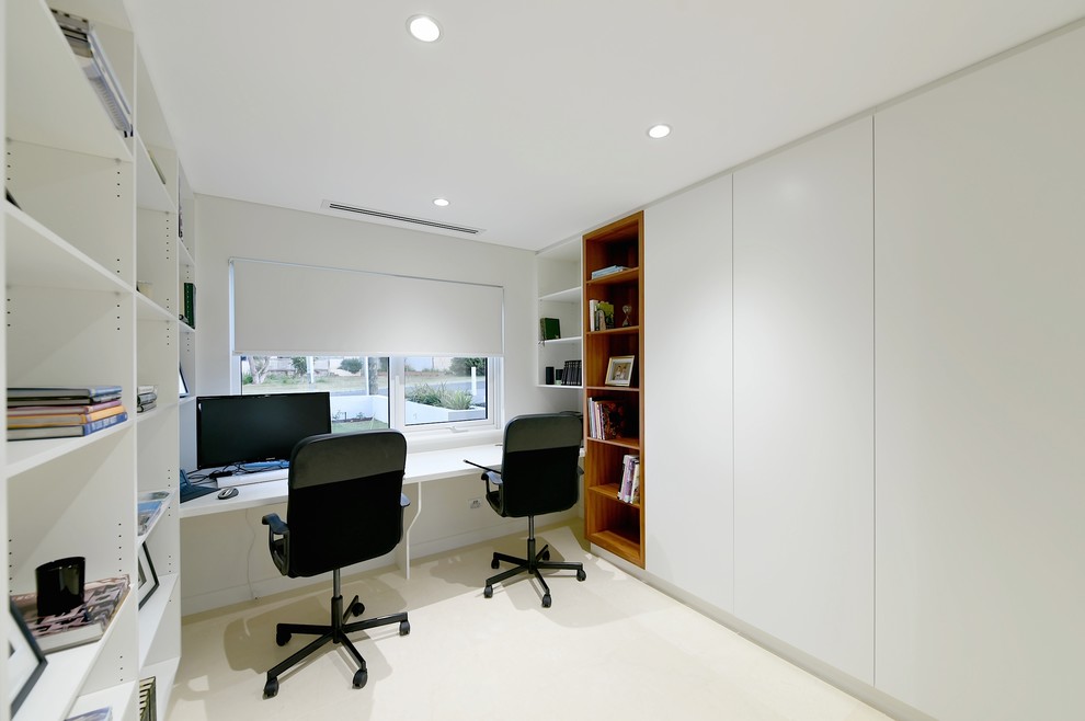 Modern inredning av ett hemmabibliotek, med vita väggar och ett inbyggt skrivbord