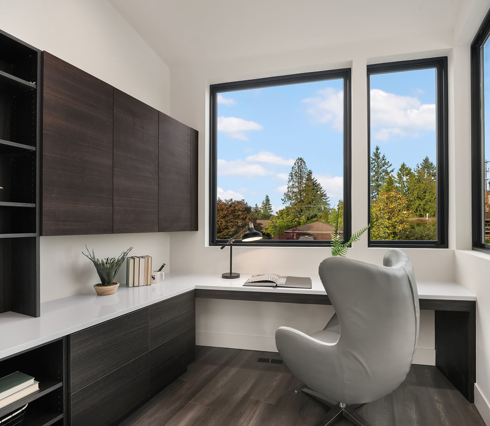 Diseño de despacho contemporáneo sin chimenea con paredes blancas, escritorio empotrado y suelo marrón