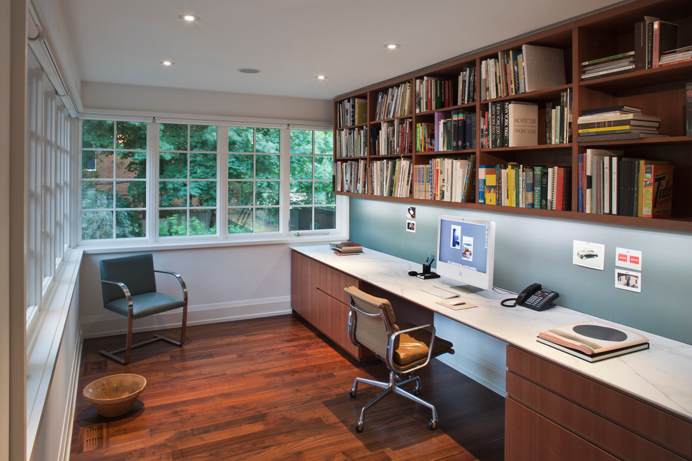 Foto de despacho actual de tamaño medio sin chimenea con paredes blancas, escritorio empotrado y suelo de madera oscura