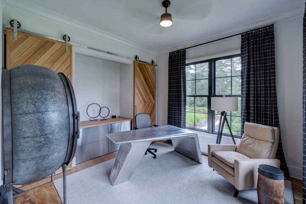 Diseño de despacho grande sin chimenea con paredes blancas, suelo de madera clara, escritorio independiente y suelo marrón
