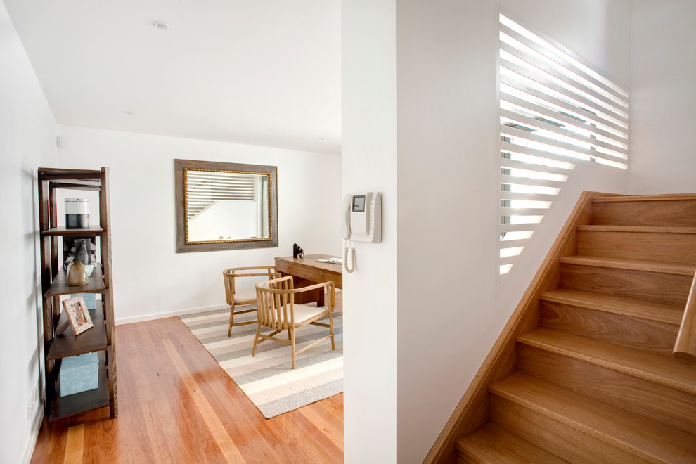 Cette image montre un bureau minimaliste de taille moyenne avec un mur blanc, un sol en bois brun et un bureau indépendant.
