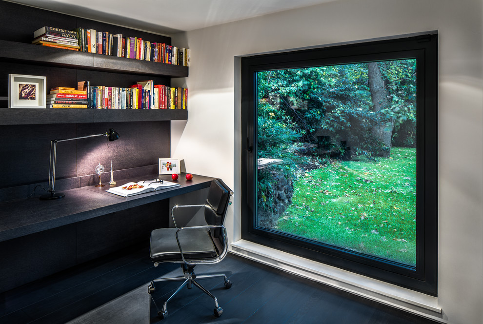 Cette photo montre un bureau tendance avec un mur blanc, parquet foncé et un bureau intégré.