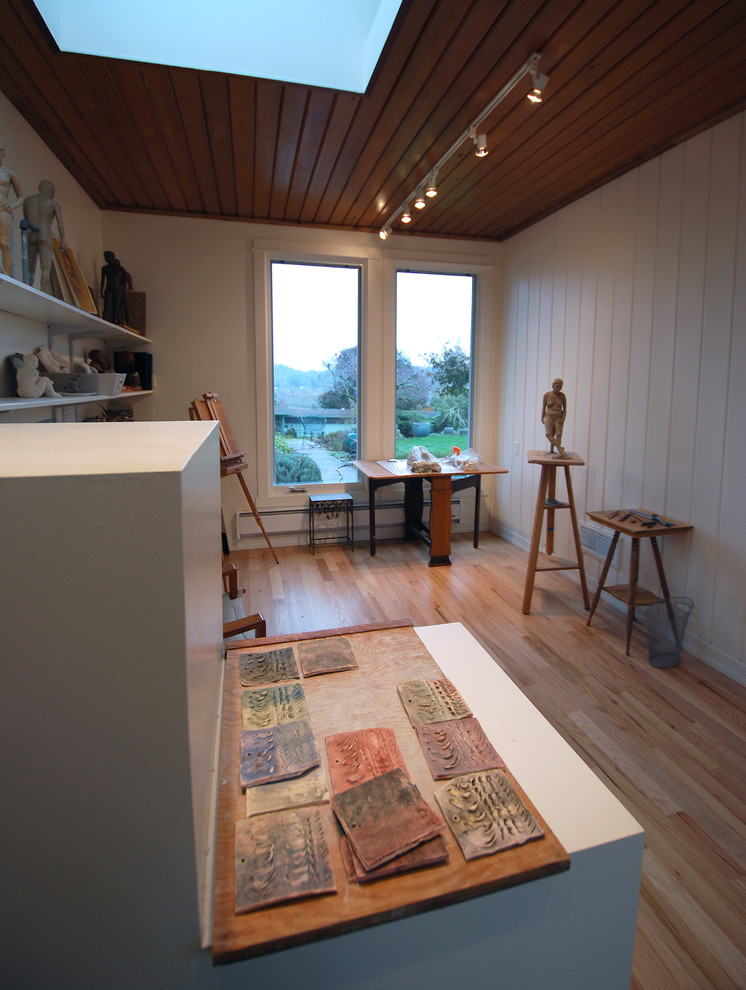 Modern inredning av ett litet hemmastudio, med vita väggar och mellanmörkt trägolv