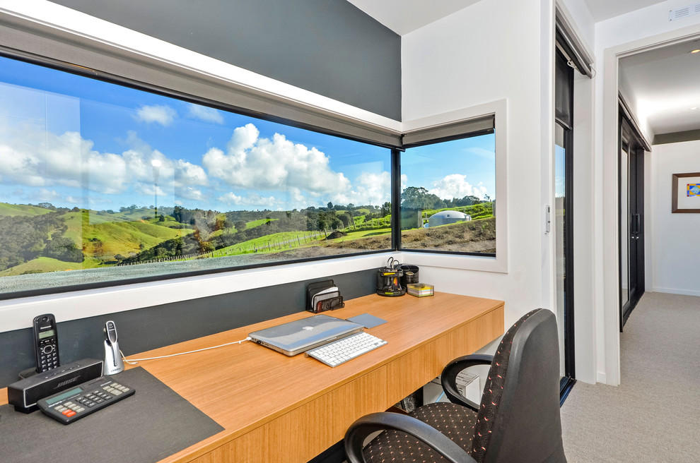Ejemplo de despacho moderno de tamaño medio sin chimenea con paredes grises, moqueta, escritorio empotrado y suelo beige