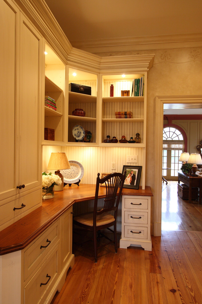 Example of a small classic built-in desk medium tone wood floor study room design in DC Metro with white walls