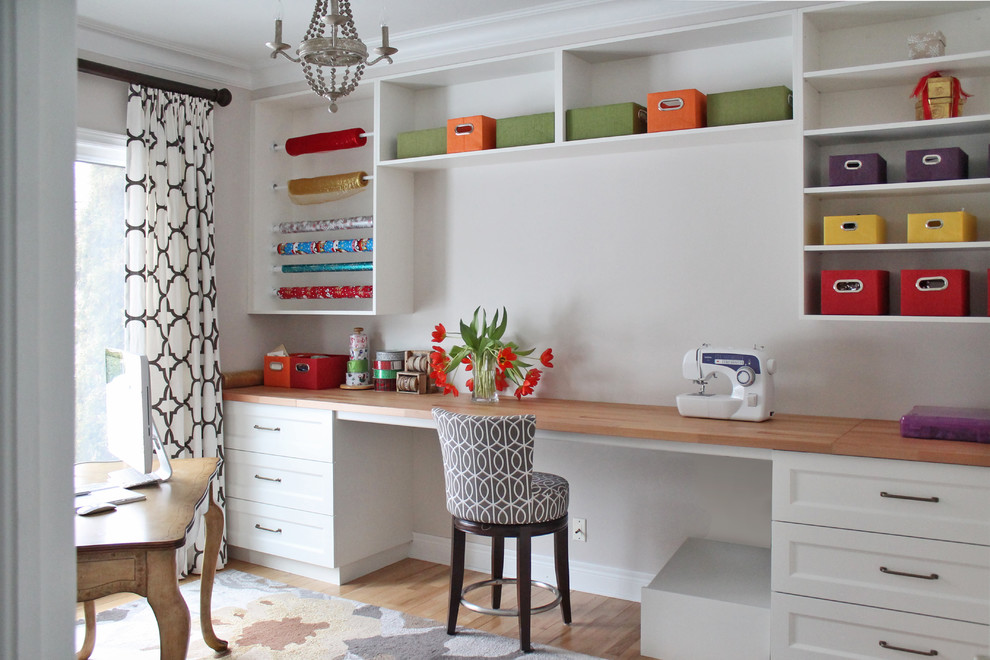 Ejemplo de sala de manualidades clásica renovada de tamaño medio con paredes beige, suelo de madera clara, escritorio empotrado y suelo beige
