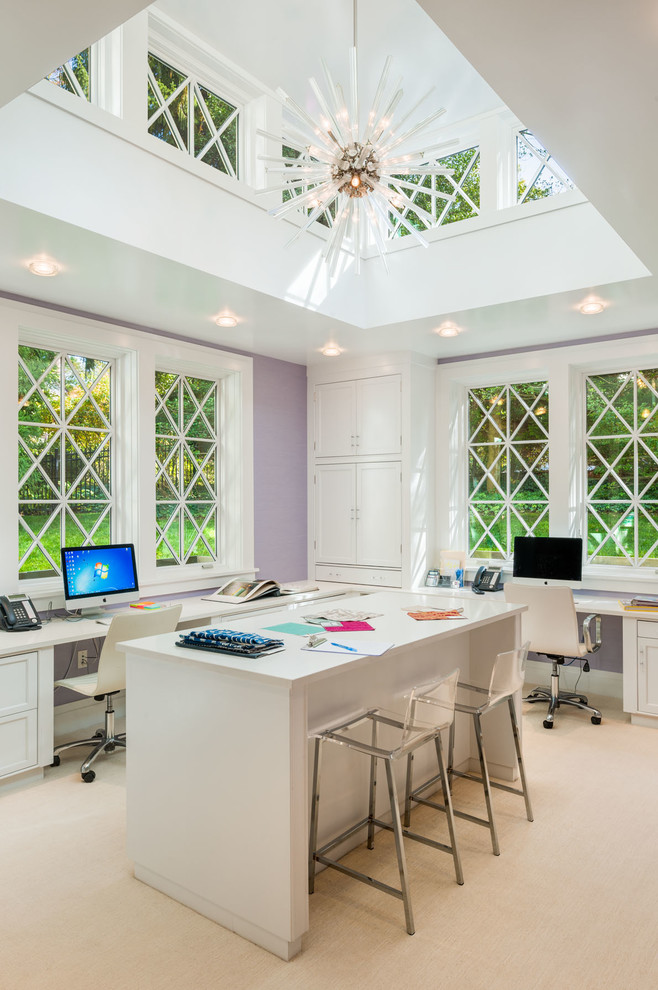 Klassisk inredning av ett hemmastudio, med lila väggar, heltäckningsmatta, ett inbyggt skrivbord och beiget golv