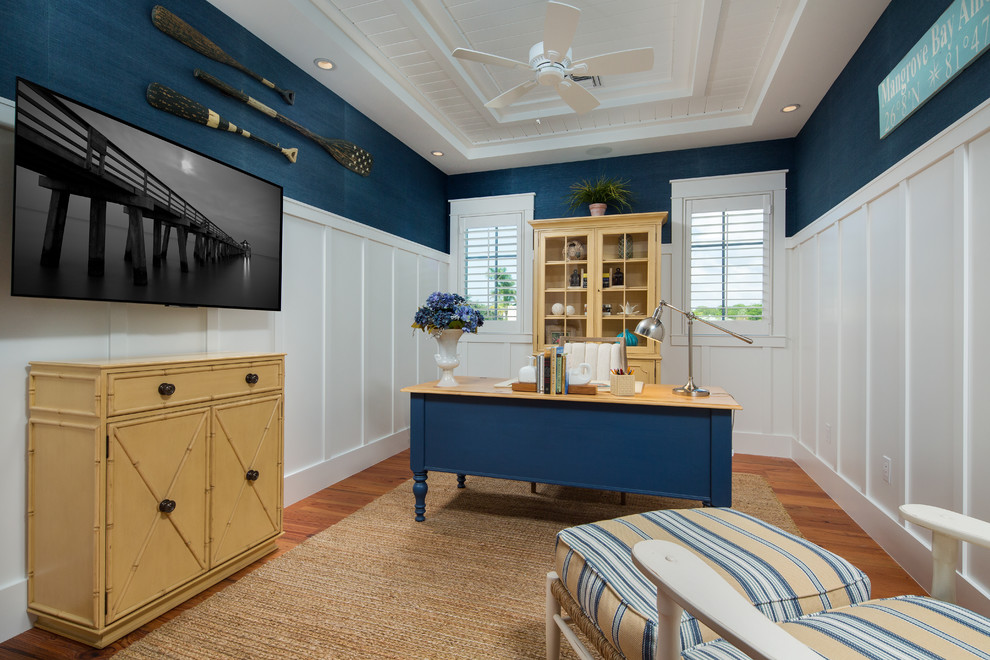 Ispirazione per uno studio stile marino di medie dimensioni con pareti blu, pavimento in legno massello medio, nessun camino, scrivania autoportante e pavimento marrone