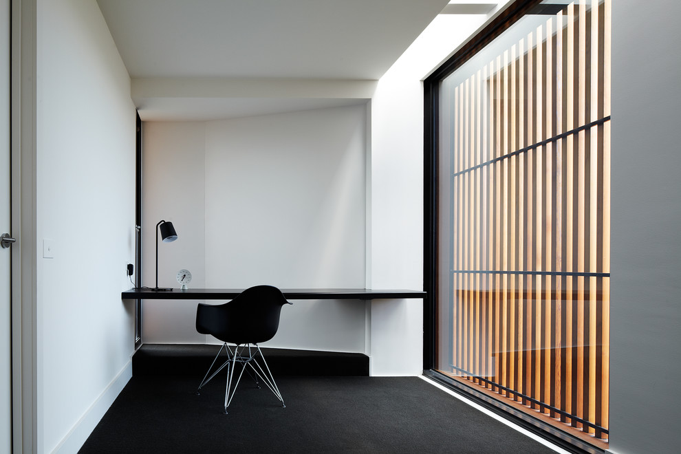 Cette image montre un bureau design avec un mur blanc, moquette et un bureau intégré.