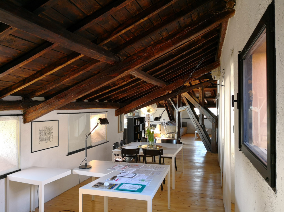 Photo of a large modern home studio in Rome with white walls, medium hardwood flooring, a freestanding desk and beige floors.