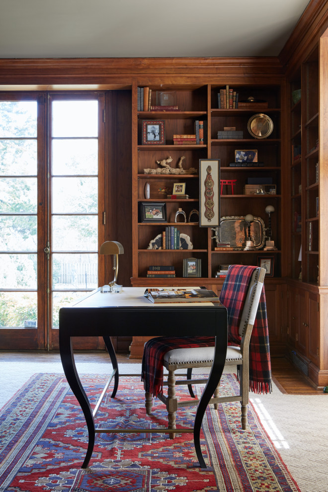 Klassisches Lesezimmer mit braunem Holzboden, Kamin, Kaminumrandung aus Stein, freistehendem Schreibtisch und braunem Boden in Nashville