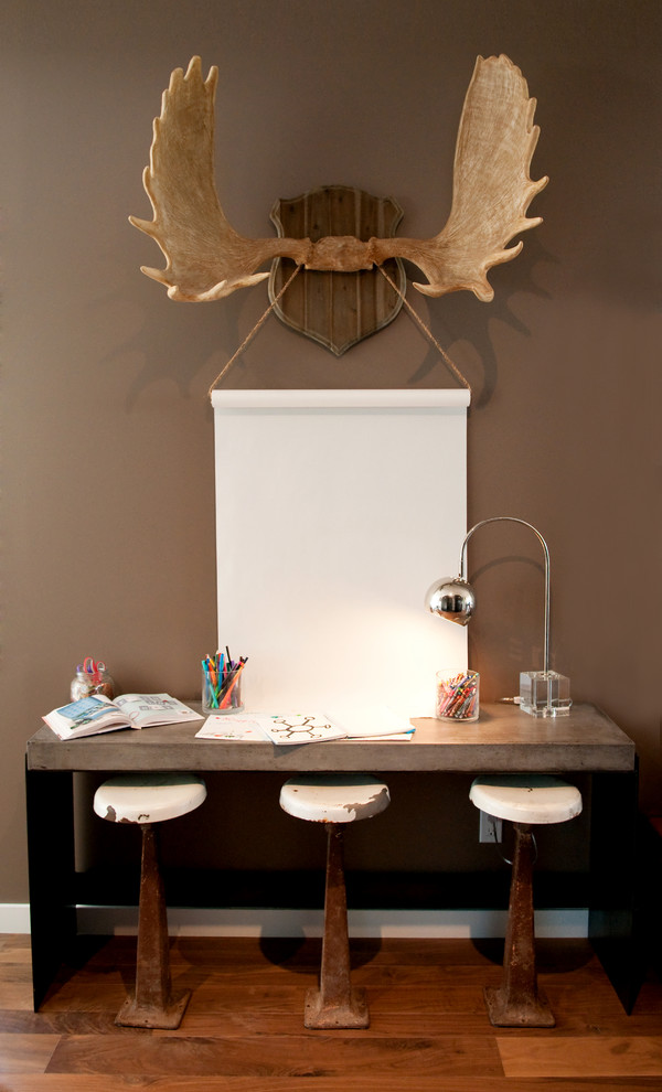 Foto på ett litet funkis arbetsrum, med bruna väggar, mellanmörkt trägolv och ett fristående skrivbord