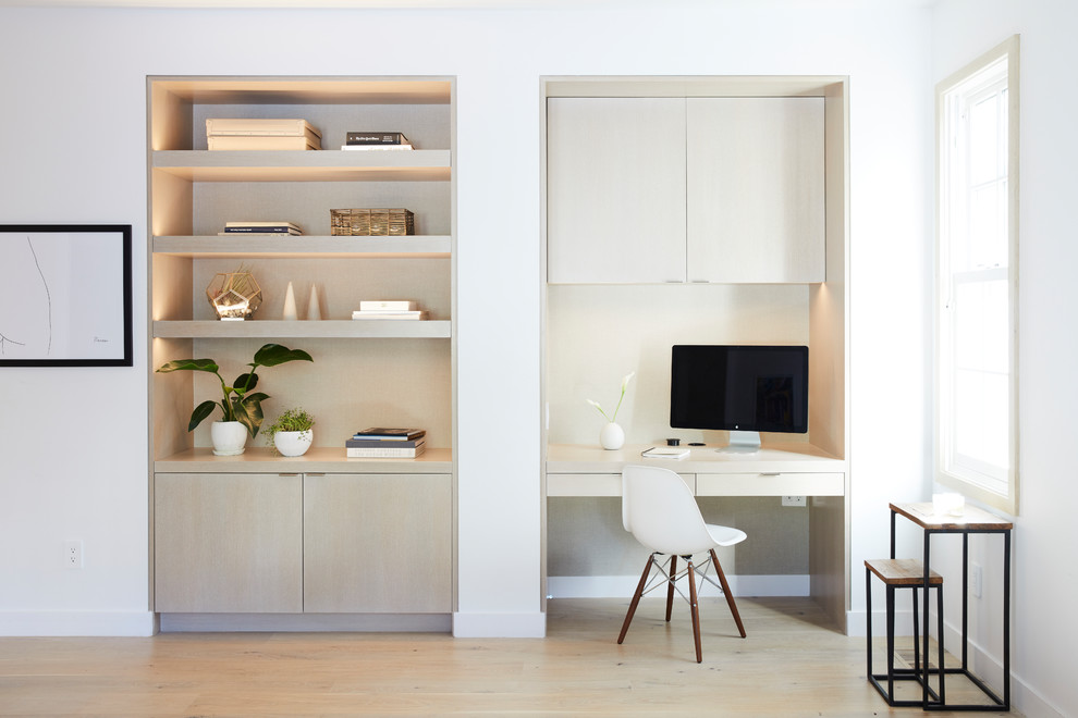 Diseño de despacho contemporáneo con paredes blancas, suelo de madera clara, escritorio empotrado y suelo beige