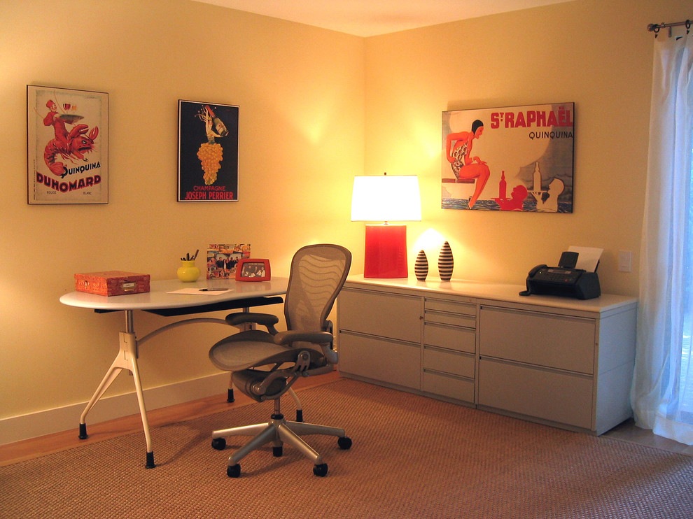 Imagen de despacho contemporáneo grande con paredes amarillas, suelo de madera clara y escritorio independiente