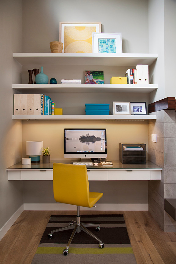 Modern inredning av ett arbetsrum, med grå väggar, ljust trägolv, en standard öppen spis, en spiselkrans i trä och ett inbyggt skrivbord