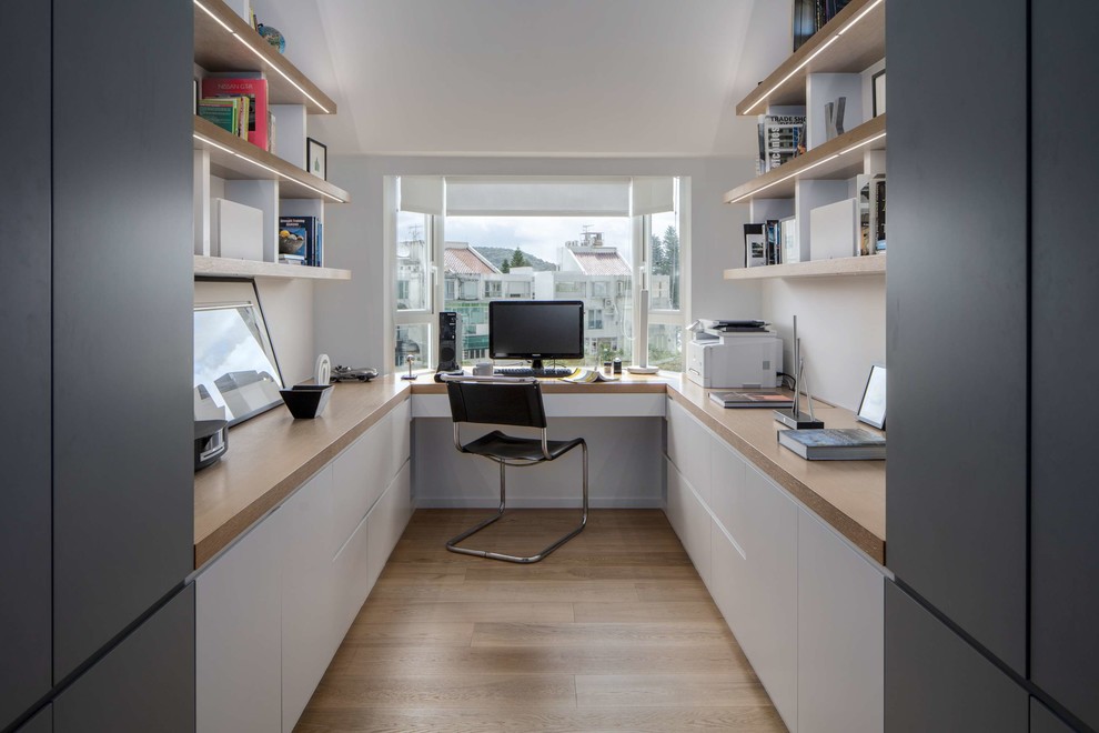 Réalisation d'un bureau design avec un mur blanc, parquet clair, un bureau intégré et un sol marron.