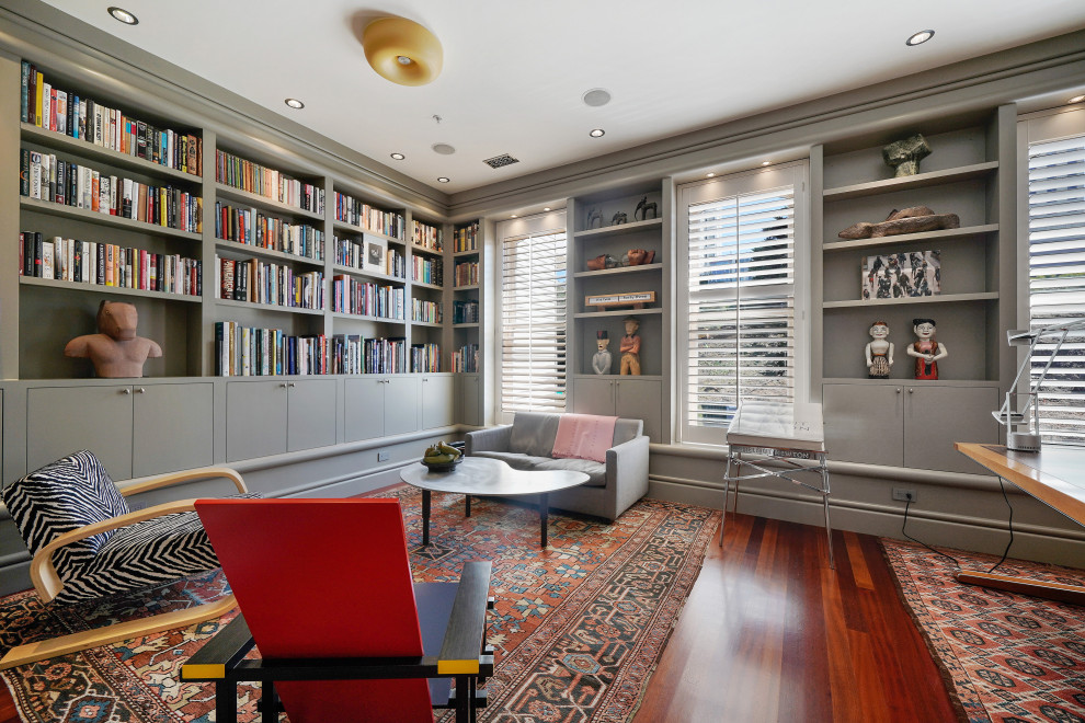 Home office library - large eclectic freestanding desk medium tone wood floor and brown floor home office library idea in San Francisco with gray walls