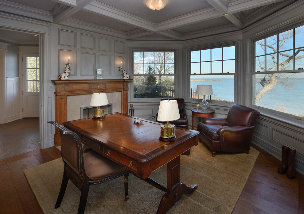 Imagen de despacho clásico con suelo de madera en tonos medios, todas las chimeneas, escritorio independiente y marco de chimenea de piedra