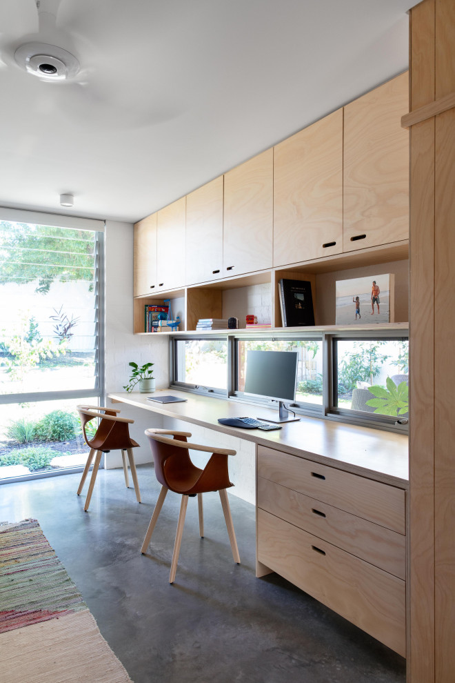 This is an example of an urban home office in Perth with white walls, concrete flooring, a built-in desk and grey floors.