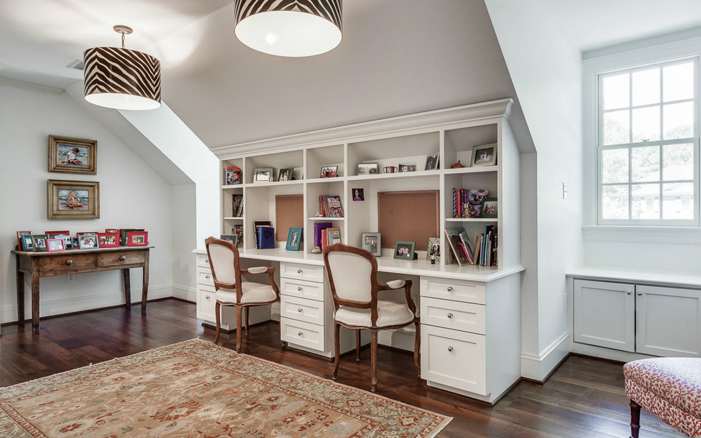 Exempel på ett klassiskt arbetsrum, med vita väggar, mörkt trägolv och ett inbyggt skrivbord
