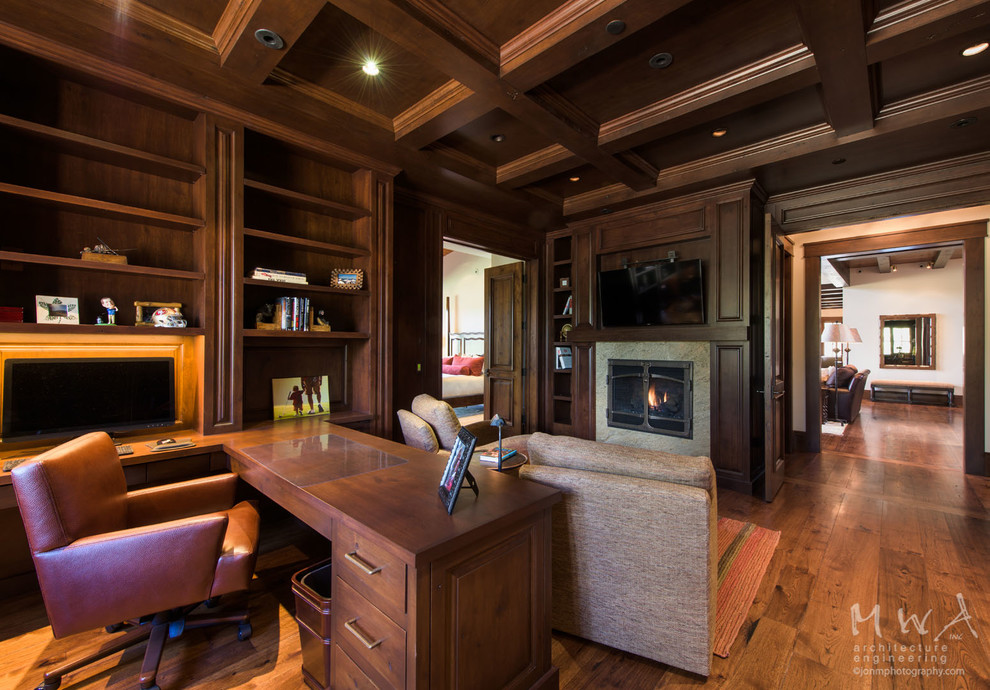 Study room - large transitional built-in desk dark wood floor and brown floor study room idea in Other with brown walls, a standard fireplace and a stone fireplace