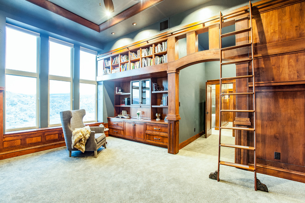 デンバーにある高級な広いトラディショナルスタイルのおしゃれなホームオフィス・書斎 (ライブラリー、緑の壁、カーペット敷き、標準型暖炉、石材の暖炉まわり、造り付け机、グレーの床) の写真