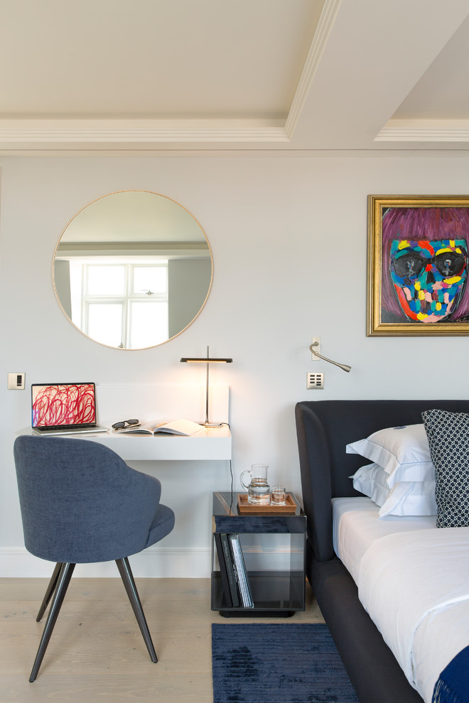 Photo of a small modern home office in London with grey walls, light hardwood flooring, a built-in desk and beige floors.