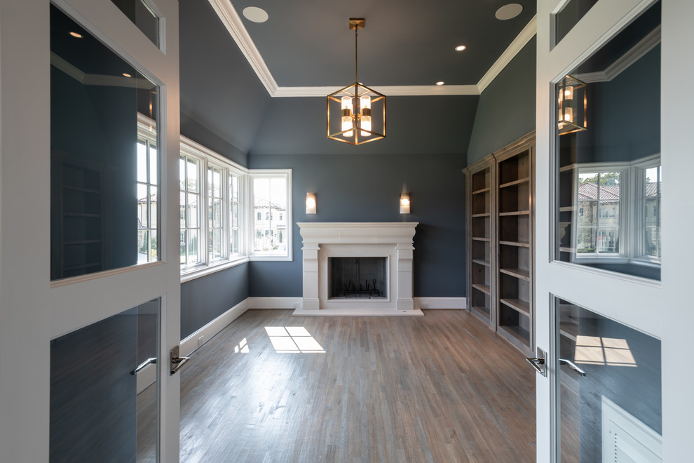 Medium sized classic study in Dallas with blue walls, medium hardwood flooring, a standard fireplace, a stone fireplace surround and brown floors.
