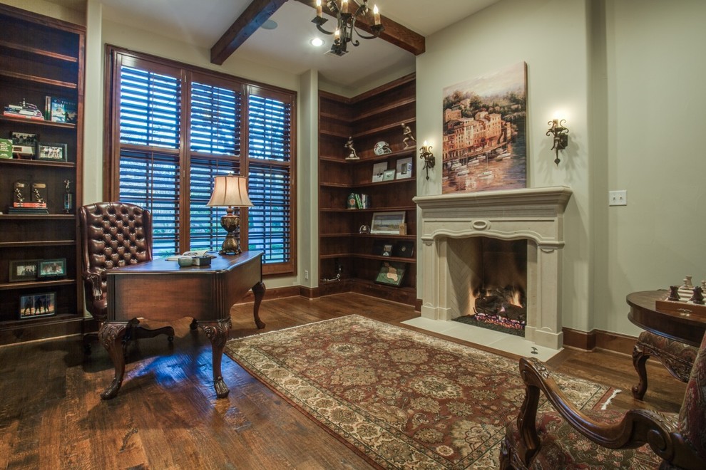 ダラスにある高級な中くらいなトラディショナルスタイルのおしゃれな書斎 (ベージュの壁、濃色無垢フローリング、標準型暖炉、漆喰の暖炉まわり、自立型机、茶色い床) の写真