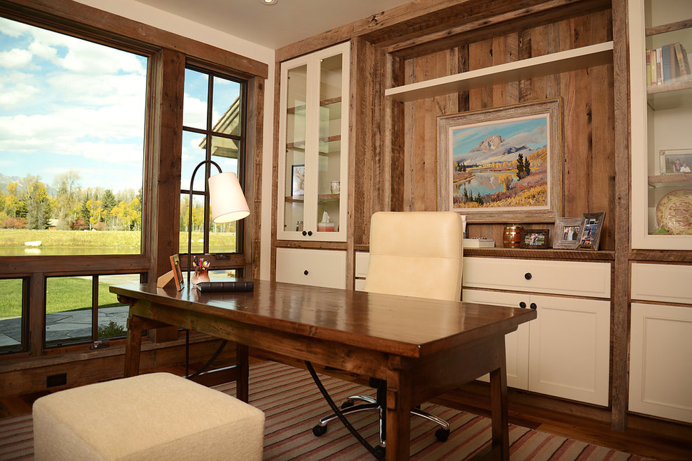 Foto de despacho rústico de tamaño medio sin chimenea con paredes beige, suelo de madera oscura y escritorio independiente